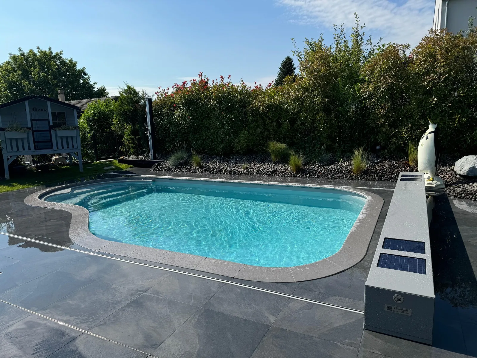Piscine haricot enterrée sur une terrasse en ardoise, réalisation Magicpool en Suisse