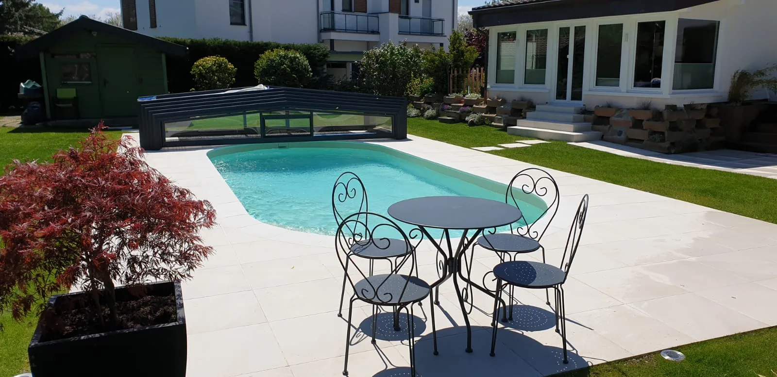 Piscine ovale avec abri télescopique et salon de jardin, réalisation Magicpool