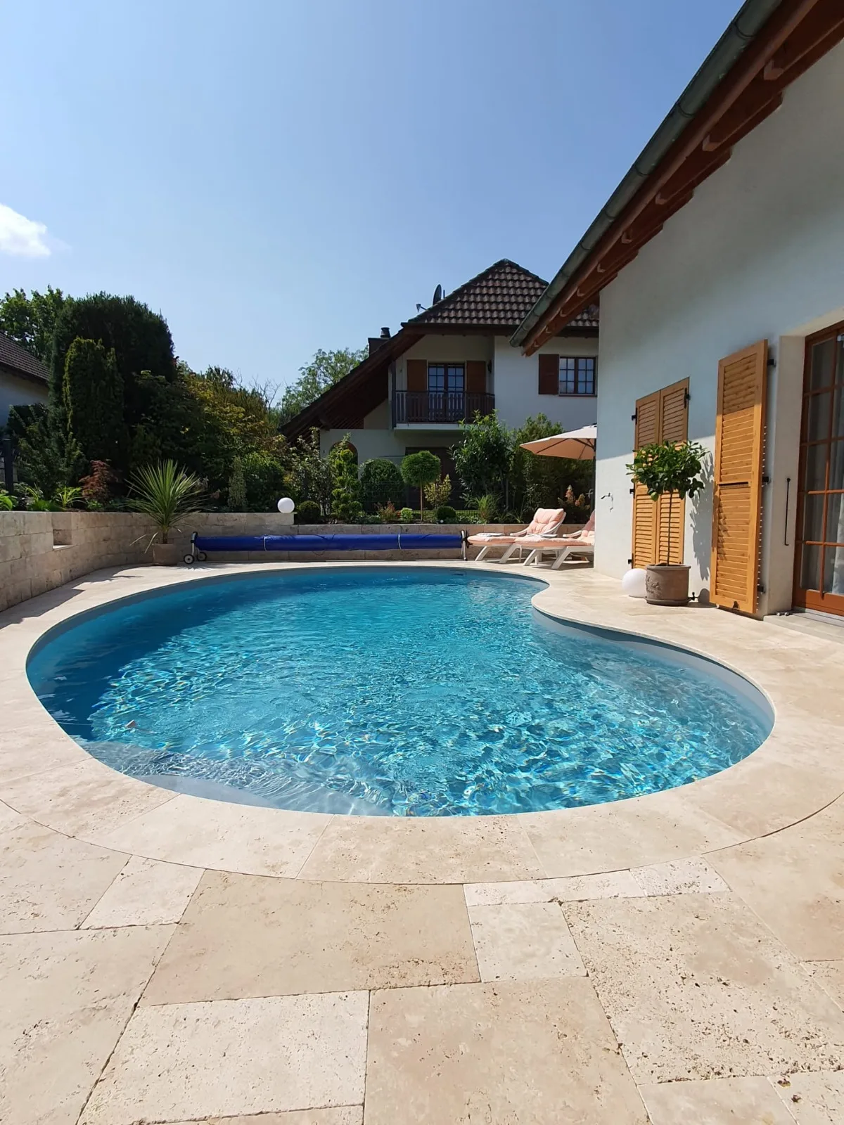 Piscine haricot avec margelles en travertin, réalisation Magicpool
