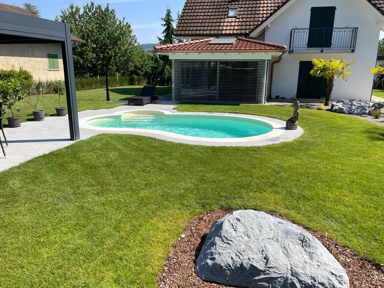 Piscine haricot dans une pelouse avec un rocher, réalisation Magicpool